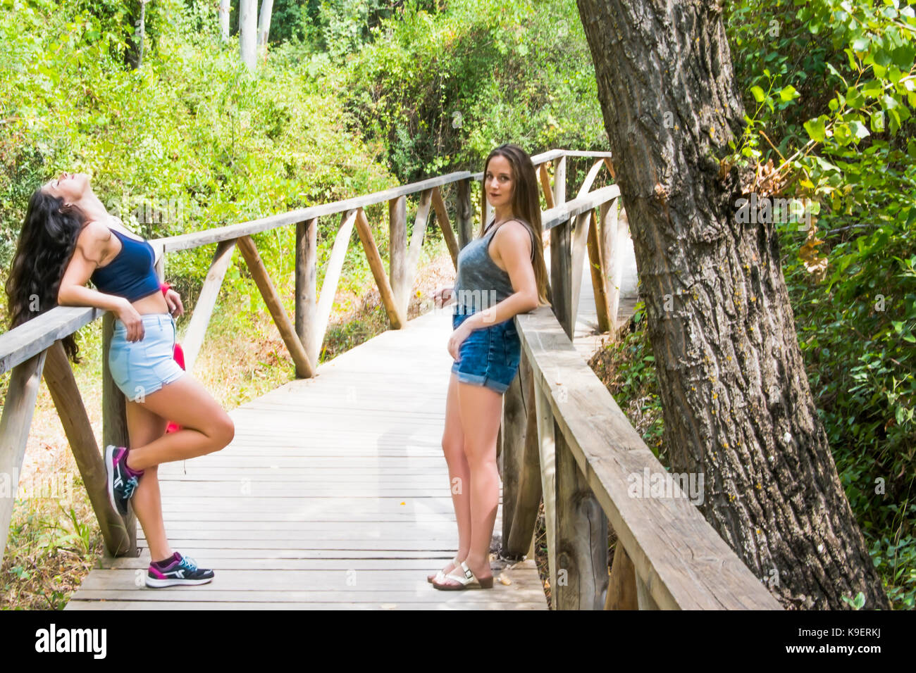 Two beautiful women hiking in nature on a wooden road Stock Photo - Alamy