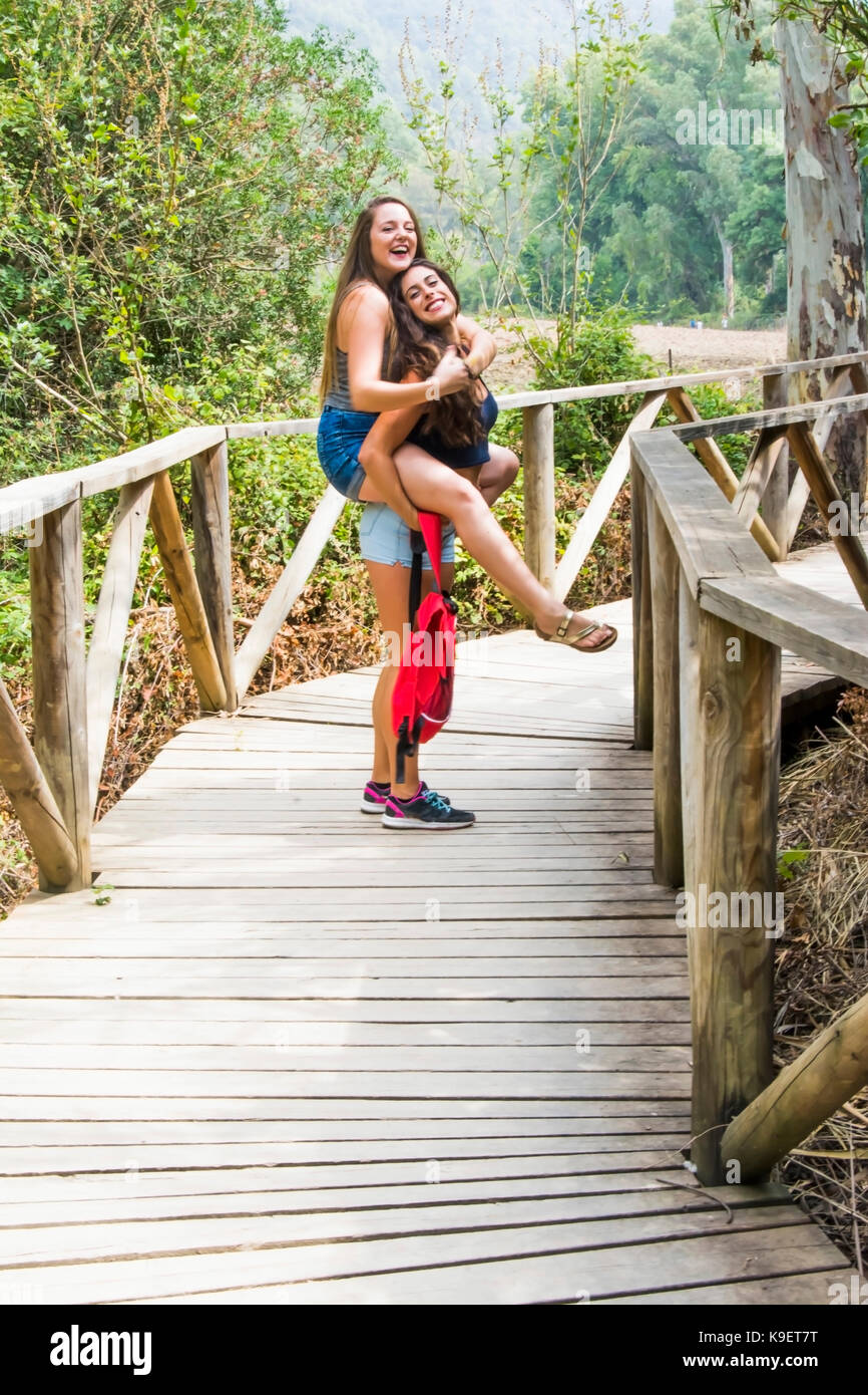 Two beautiful women hiking in nature on a wooden road Stock Photo - Alamy