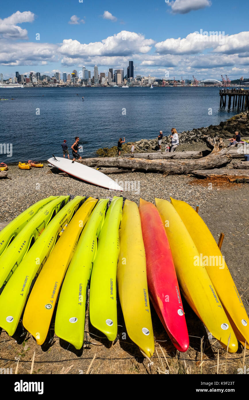 Colorful kayaks laying on the beach of West Seattle with downtown