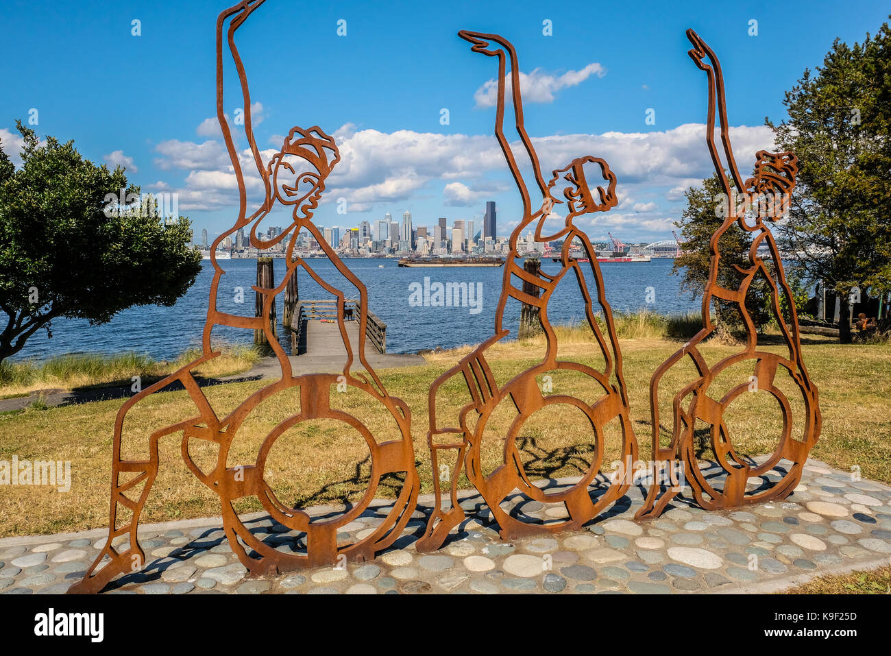 Three dancing figure metal sculptures at West Seattle with downtown Seattle in the background