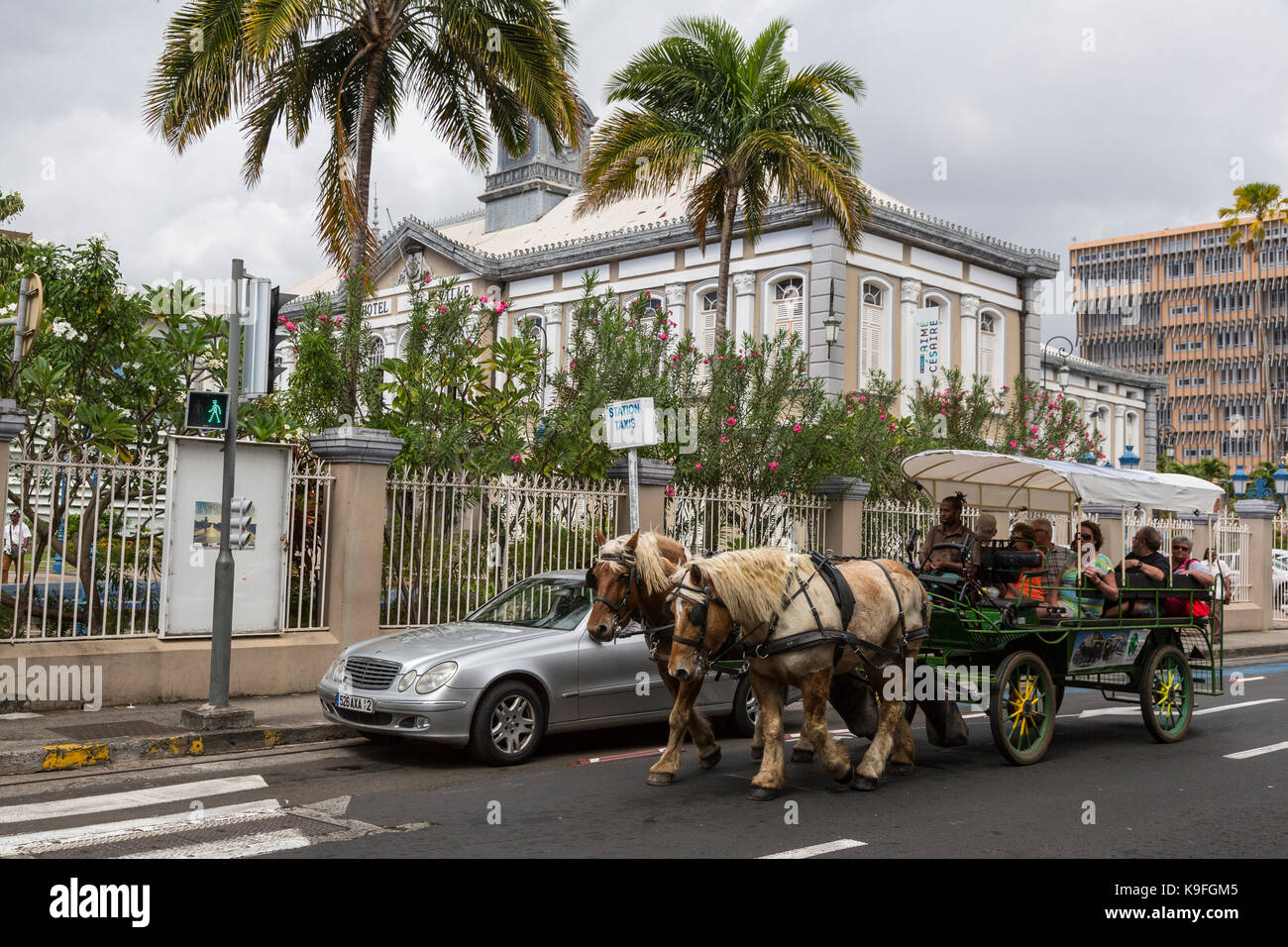 Fort-de-France, Martinique.  Tourists in a Horse-drawn Carriage Ride Past Former Hotel de Ville, Town Hall. Stock Photo