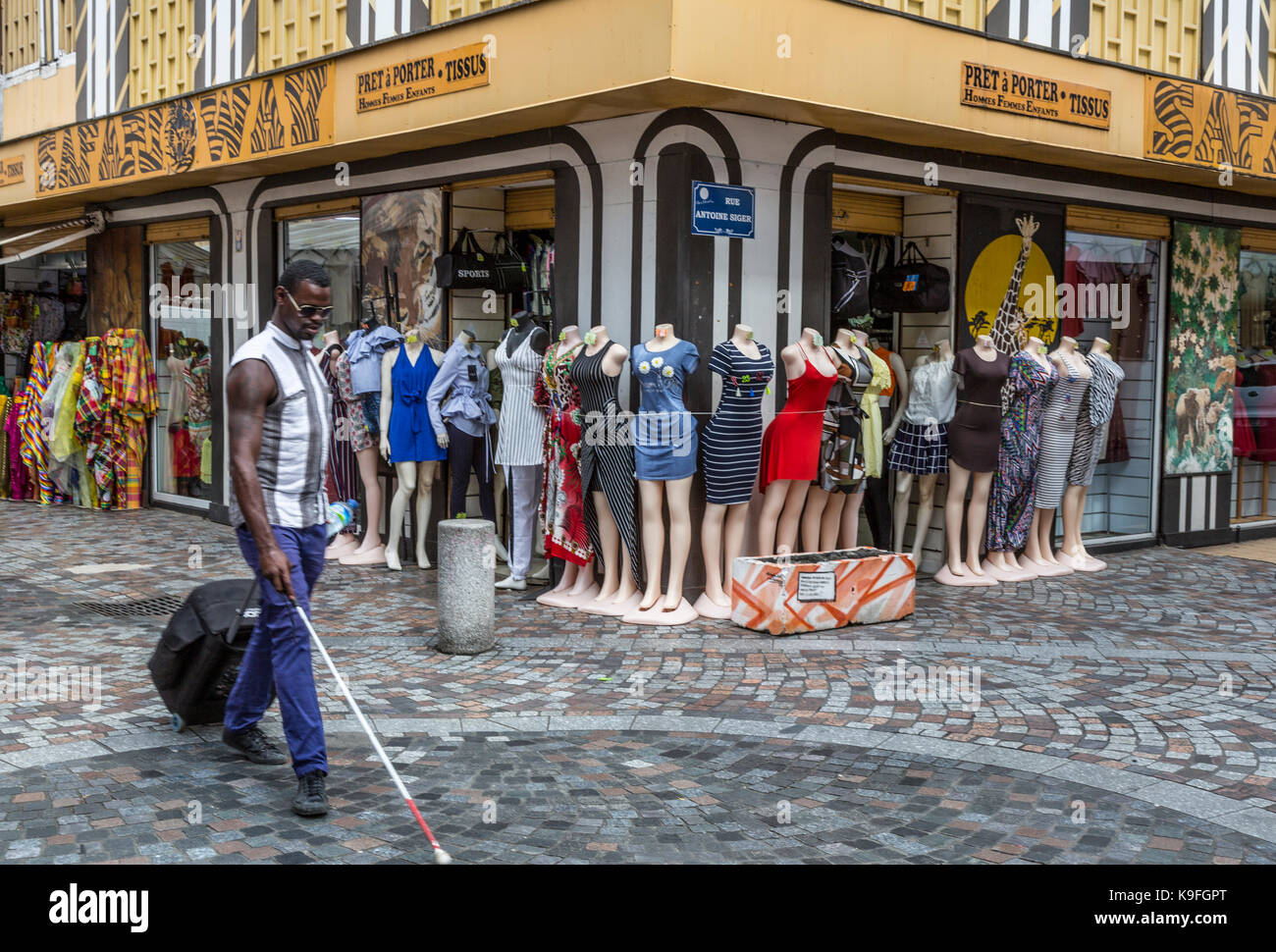 Fort-de-France, Martinique.  A Blind Man Walks Past Clothing on Display in the Rue de la Republique, a Pedestrian Walkway. Stock Photo