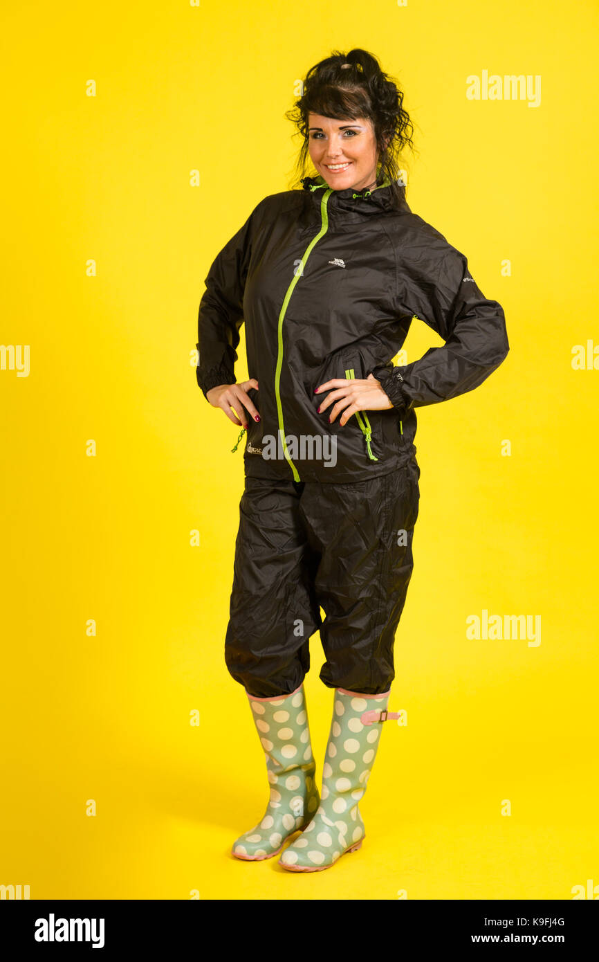 Young woman wearing rain gear on a yellow background Stock Photo