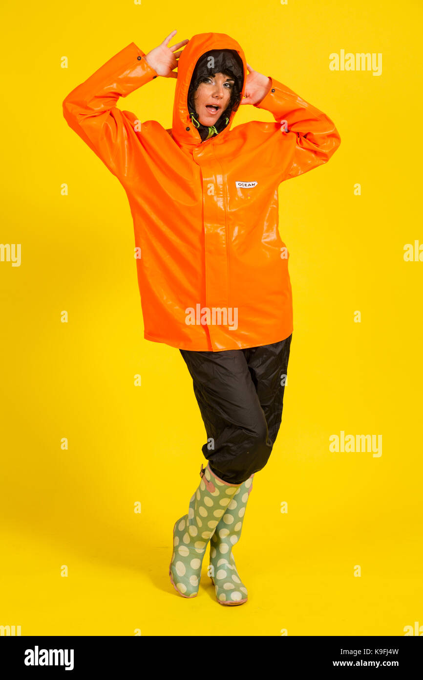 Young woman wearing rain gear on a yellow background Stock Photo