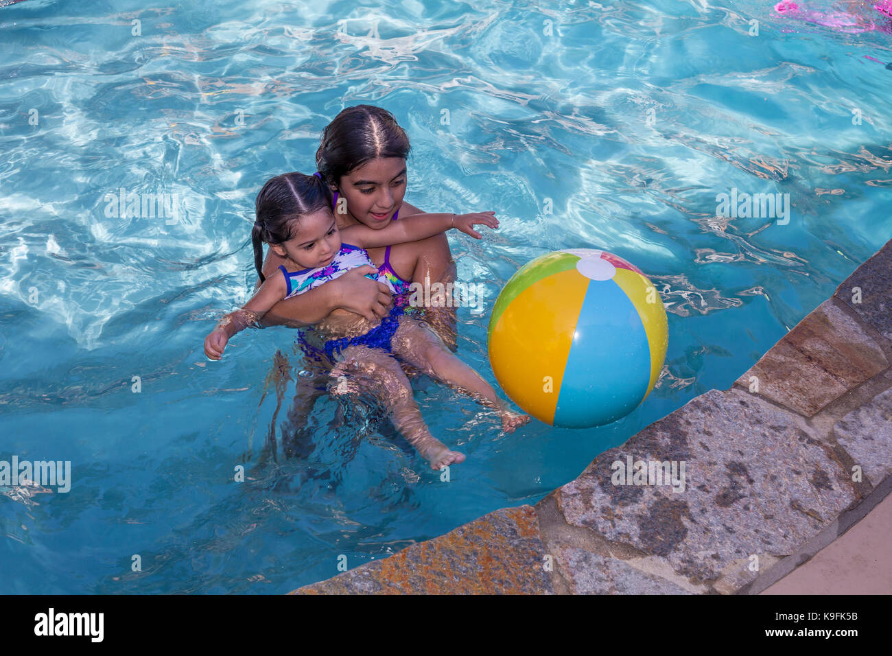 2, two, Hispanic girls, sisters, playing in swimming pool, swimming pool, fresh water swimming pool, Castro Valley, Alameda County, California Stock Photo