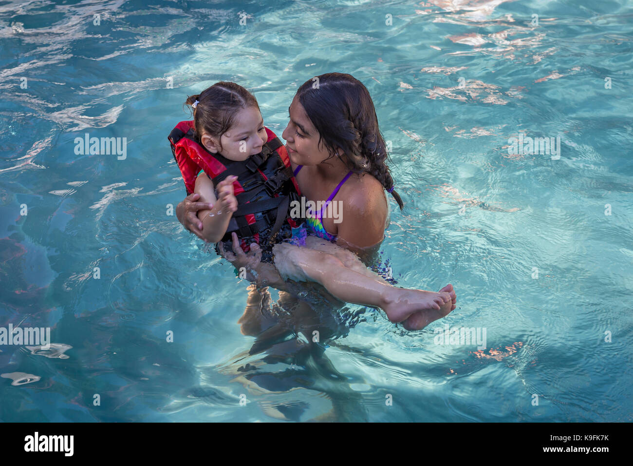 2, two, Hispanic girls, sisters, playing in swimming pool, swimming pool, fresh water swimming pool, Castro Valley, Alameda County, California Stock Photo