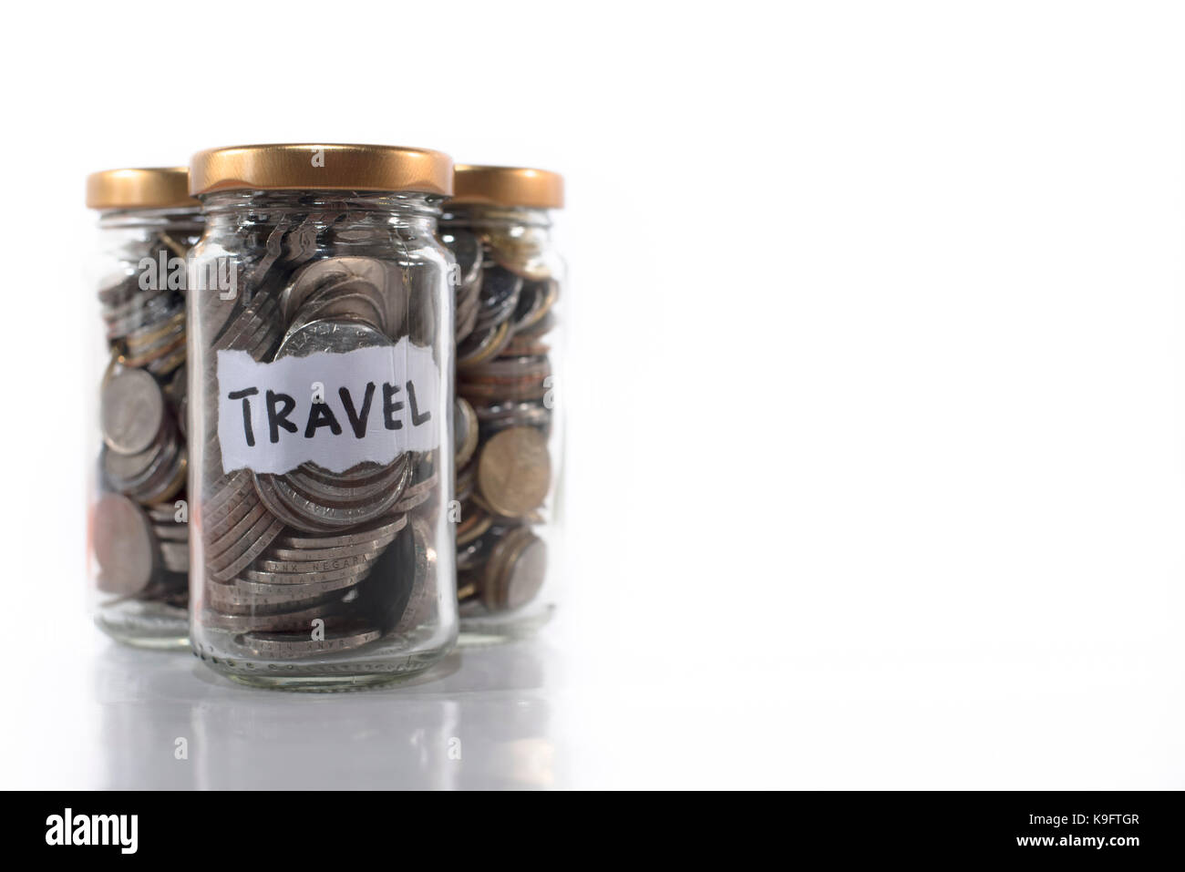 coins in a glass jar labeled ' TRAVEL ' isolated on a white background.Saving money for holidays and vacations. Saving concept and Travel concept. Stock Photo