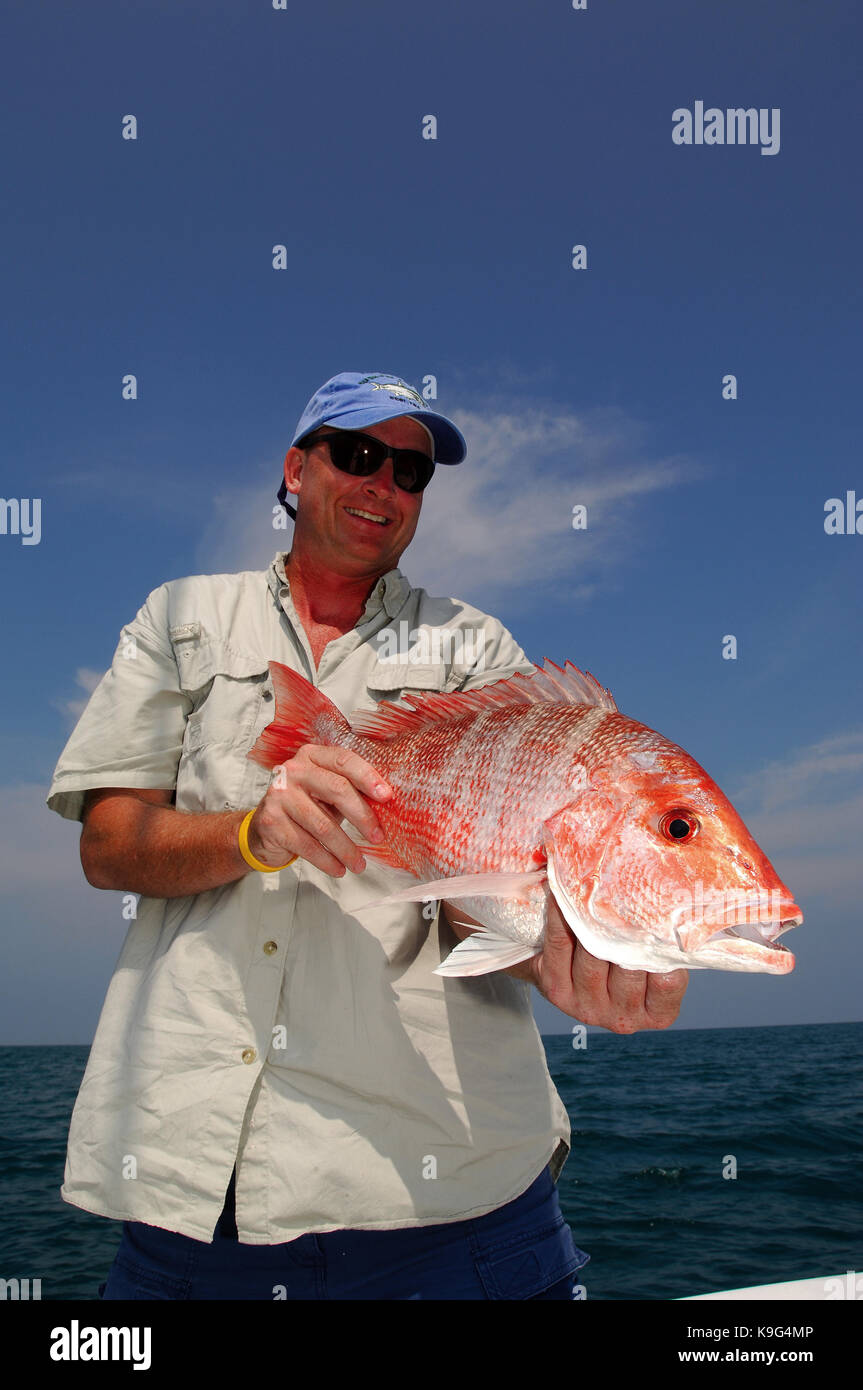 A fisherman holds a red snapper caught while deep sea fishing in
