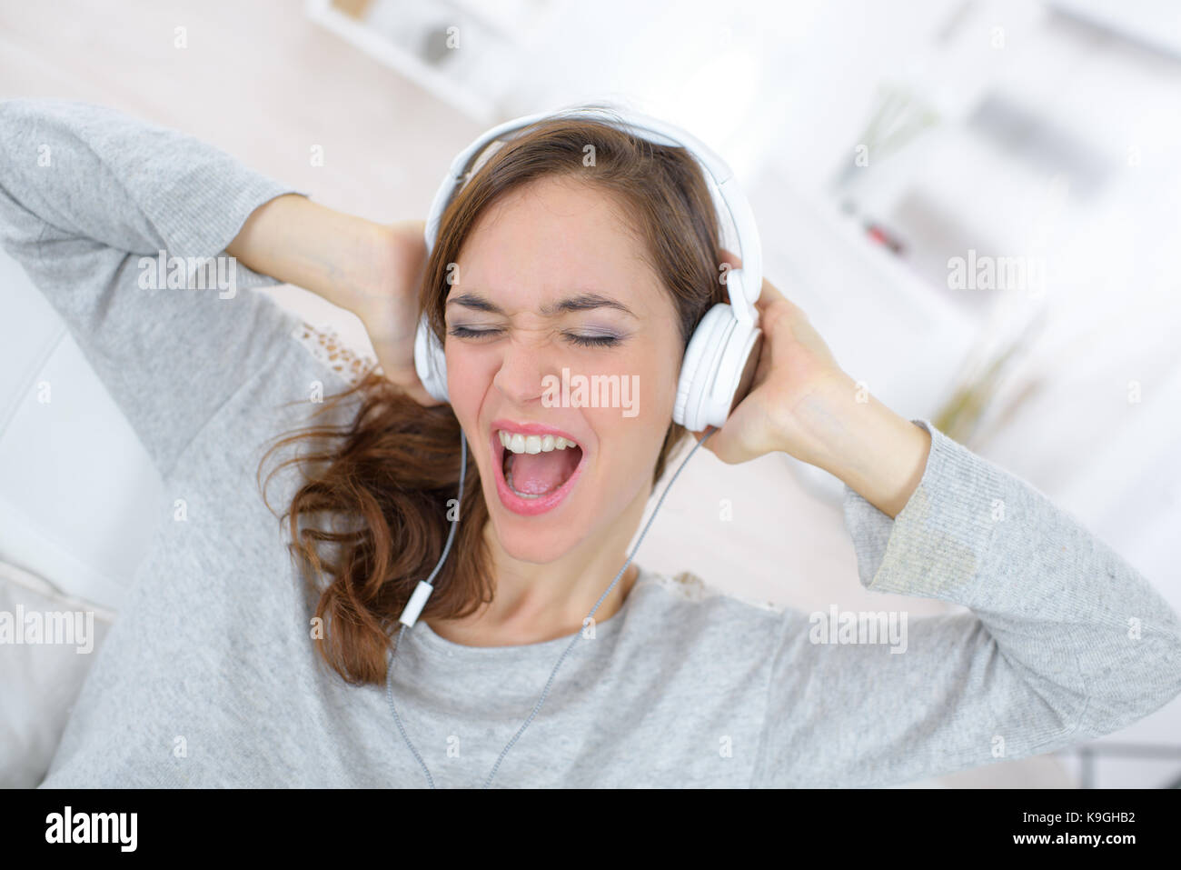 young woman listening to music on headphones and sings Stock Photo - Alamy