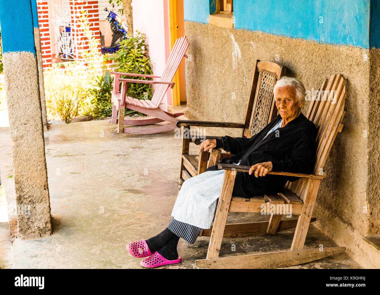 Smiling White Haired Old Lady Sitting On A Wooden Rocking Chair