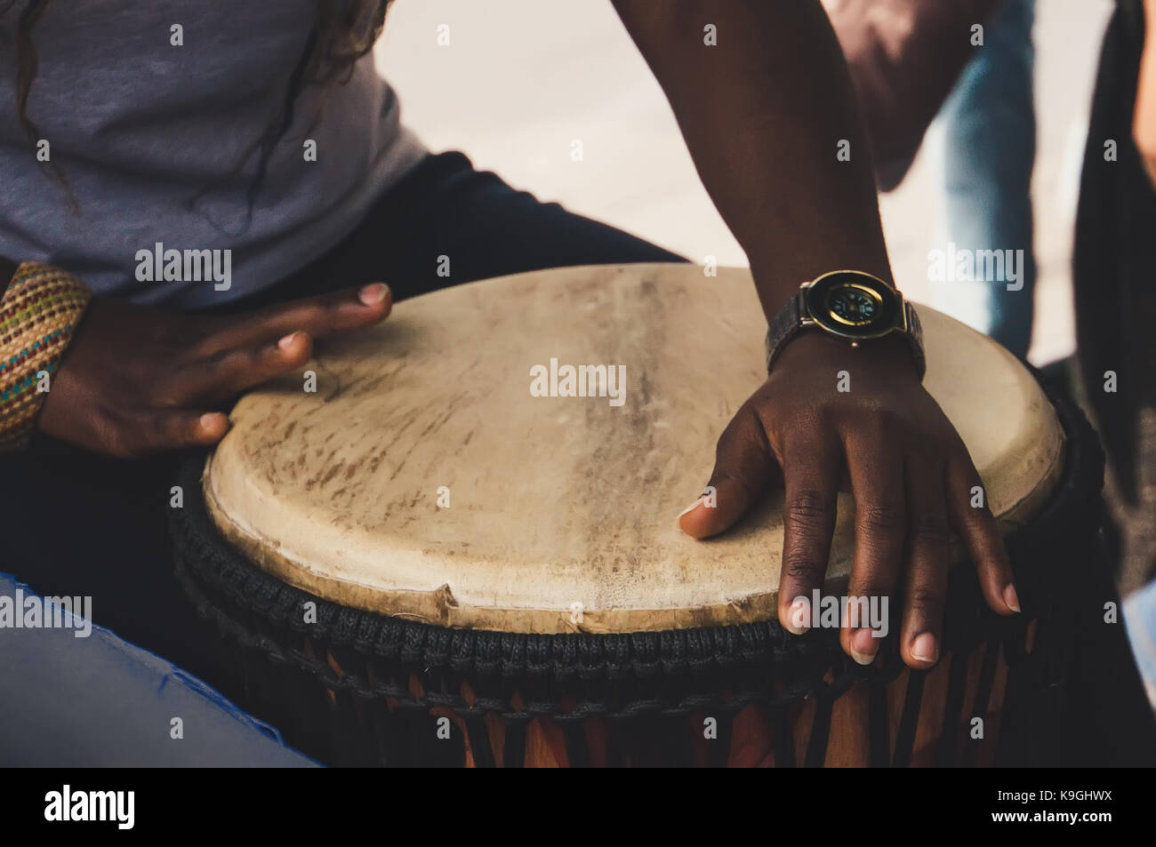 An African or Latin brown djembe conga drum being played against. Hands