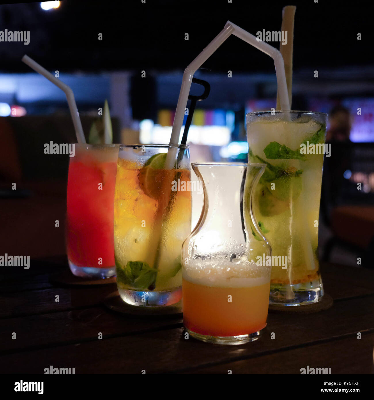 Different colorful drinks served in glasses rowed up along arranged with a soft light on a