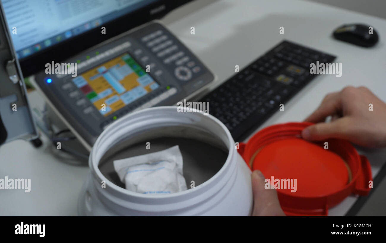 Chemical scientist opening white unlabeled plastic tank canister with ...