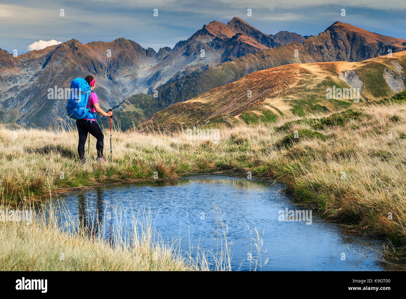Hiker woman with backpack and mountain equipment,looking at view in Fagaras mountains, Carpathians, Transylvania, Romania, Europe Stock Photo