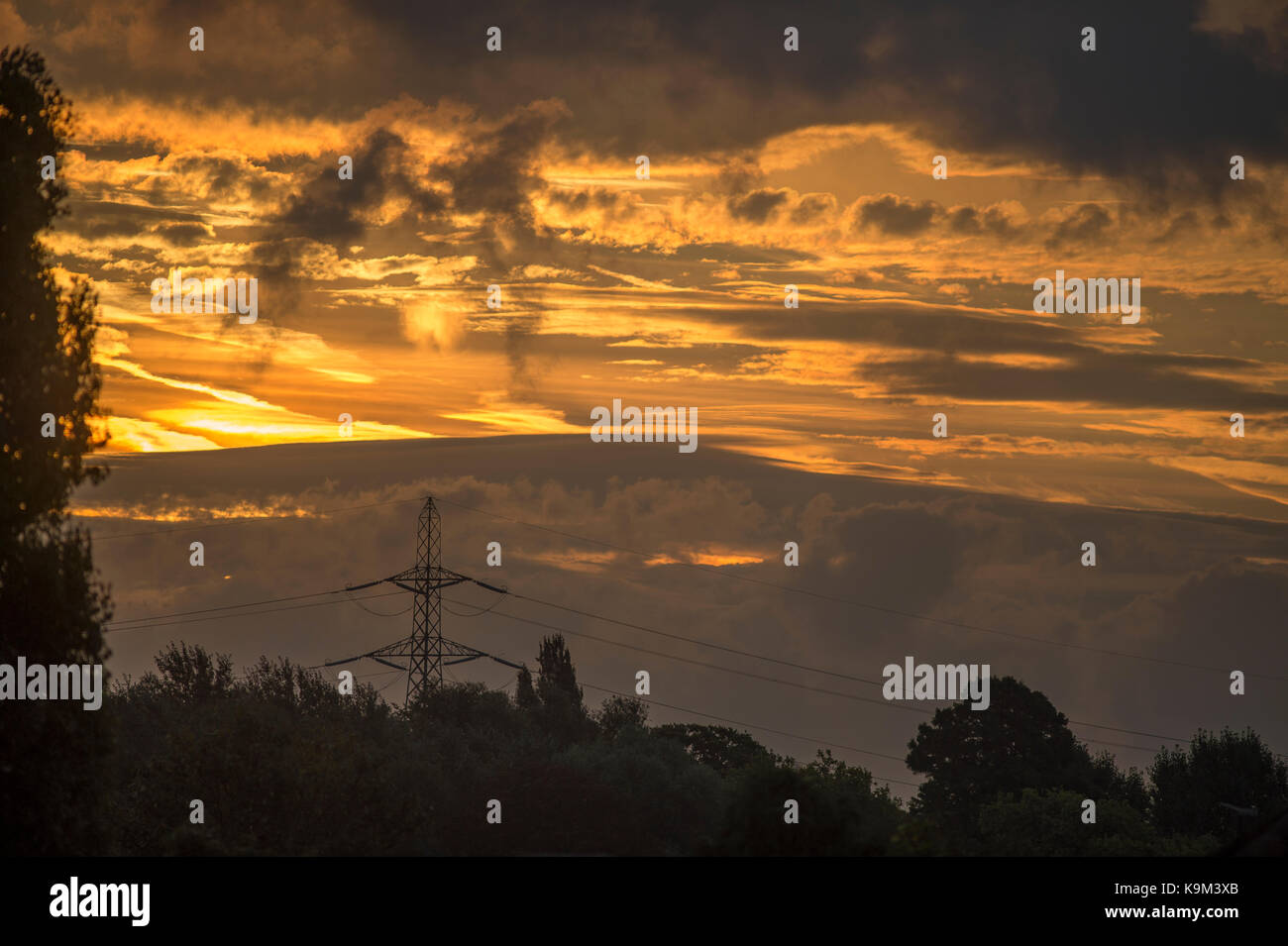 Power lines and pylon with cloudy sunrise, London, UK Stock Photo - Alamy