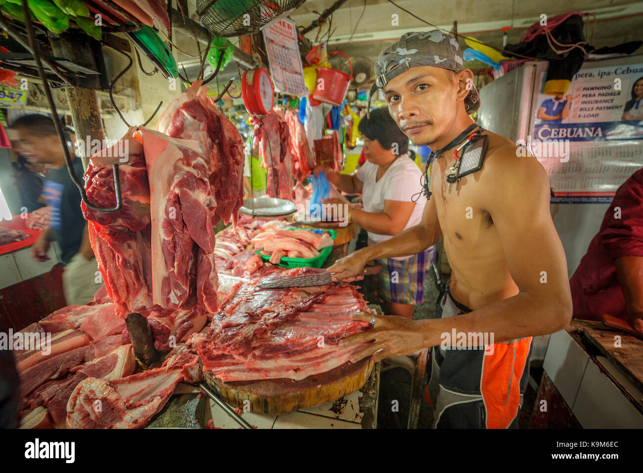A Filipino man butchers raw pork at his stall in the meat market at Puerto Princesa, Palawan Island, Philippines, Southeast Asia. Stock Photo