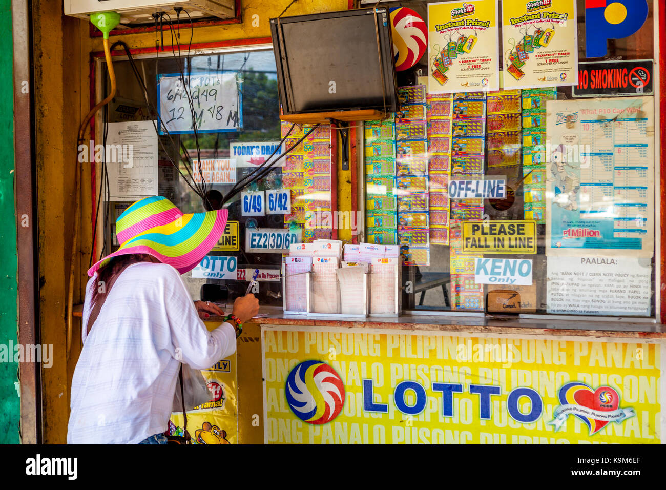 Filipino woman fills out her Lotto gambling ticket at a local outlet in Puerto Princesa, Palawan, Philippines. Stock Photo