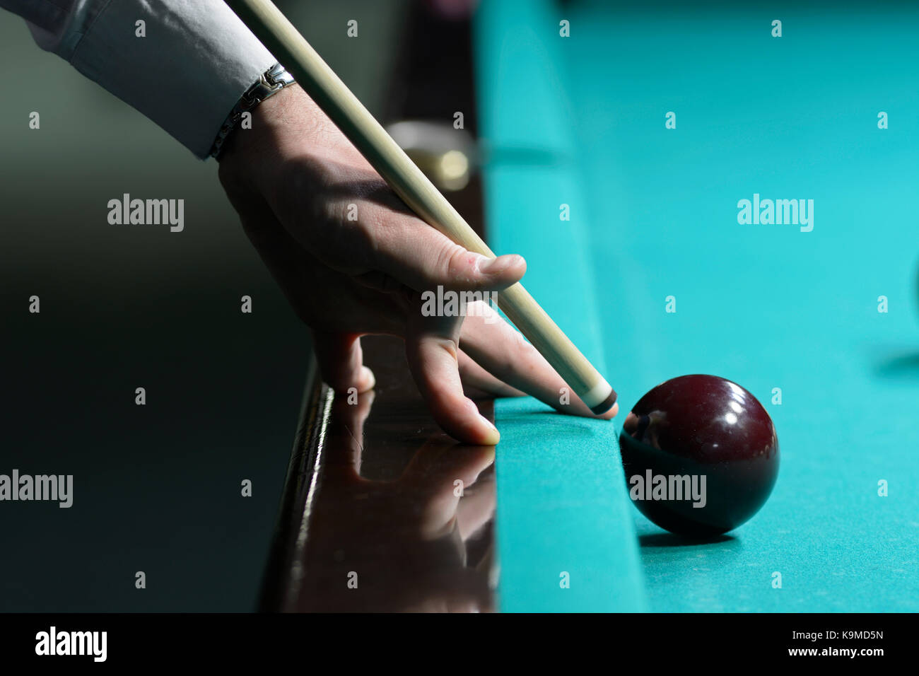 A player's arm with a cue on a pool table ready to stroke a ball Stock Photo