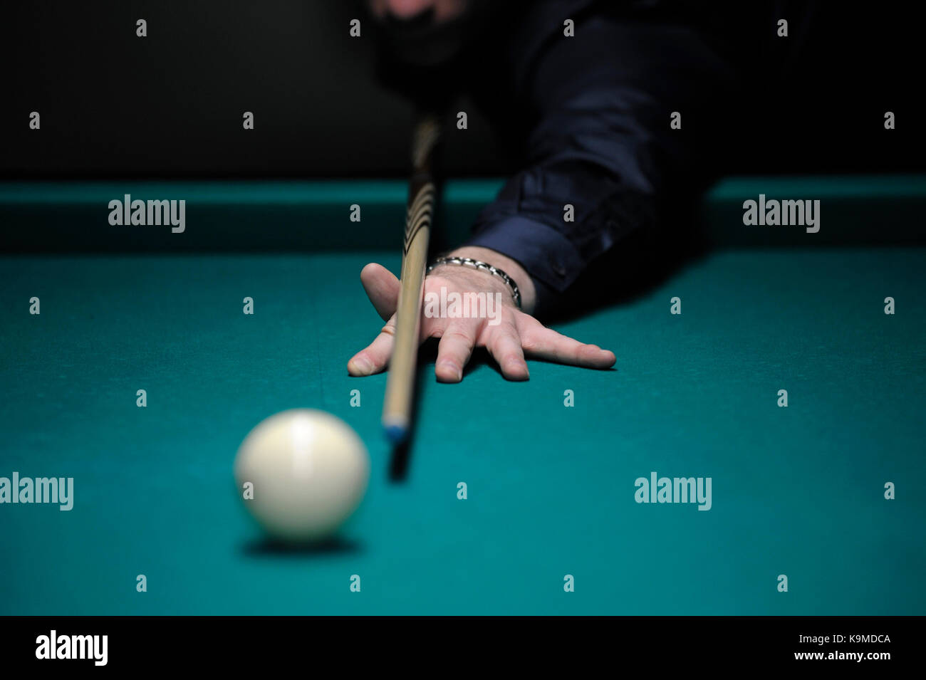 A player's arm with a cue on a pool table ready to stroke a ball Stock Photo