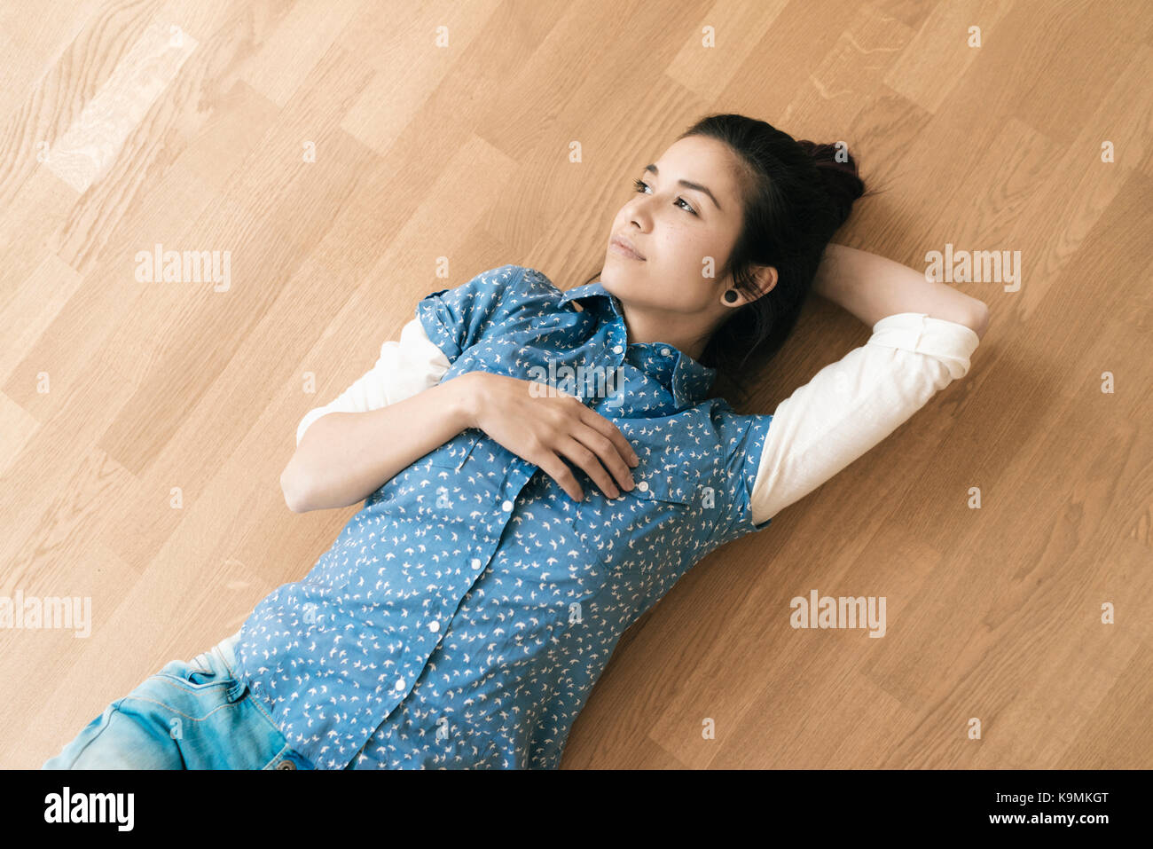 Woman lying on wooden floor Stock Photo