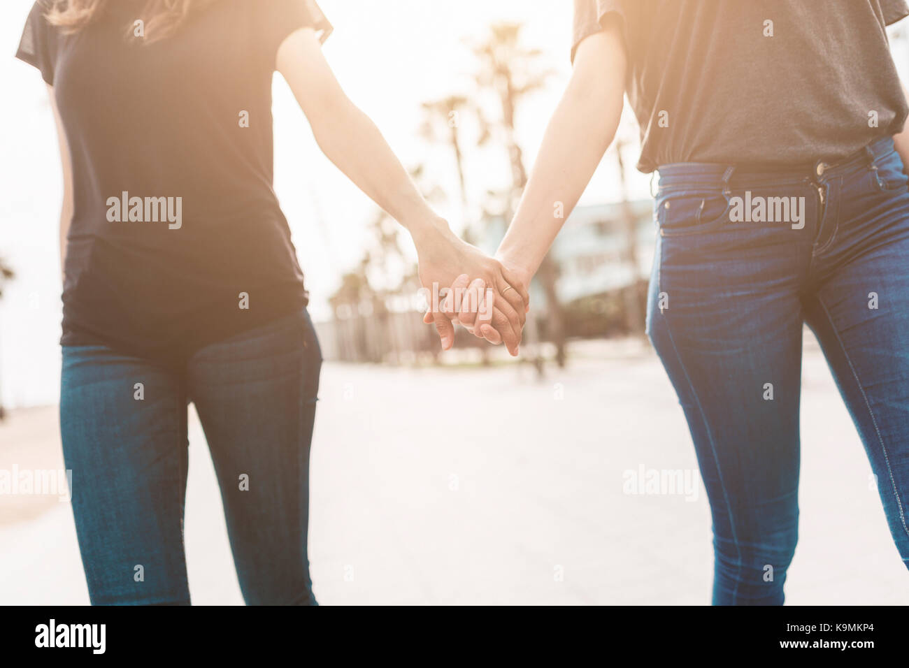 Two young women walking hand in hand on the boardwalk Stock Photo - Alamy
