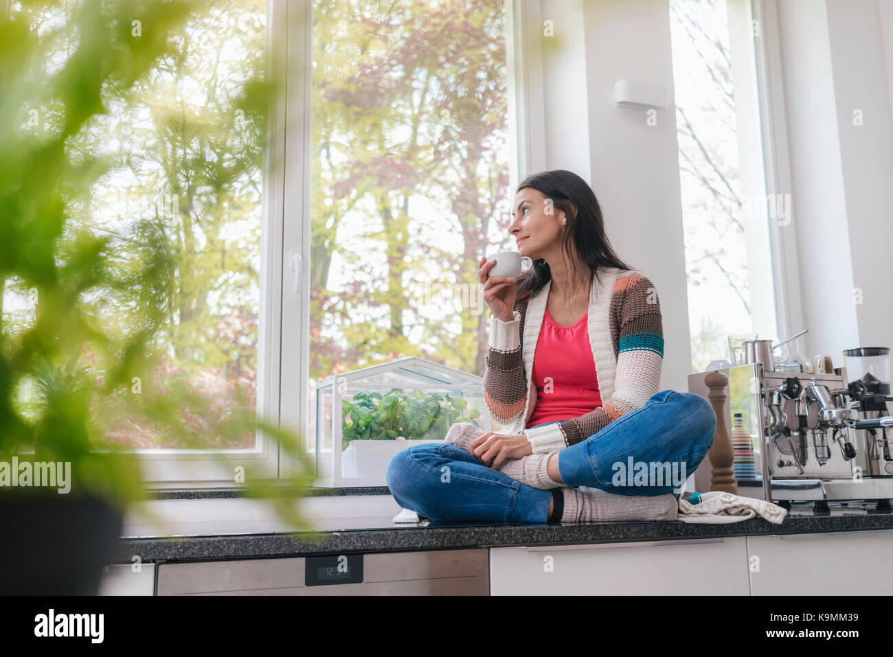 Woman in kitchen looking out of window Stock Photo - Alamy