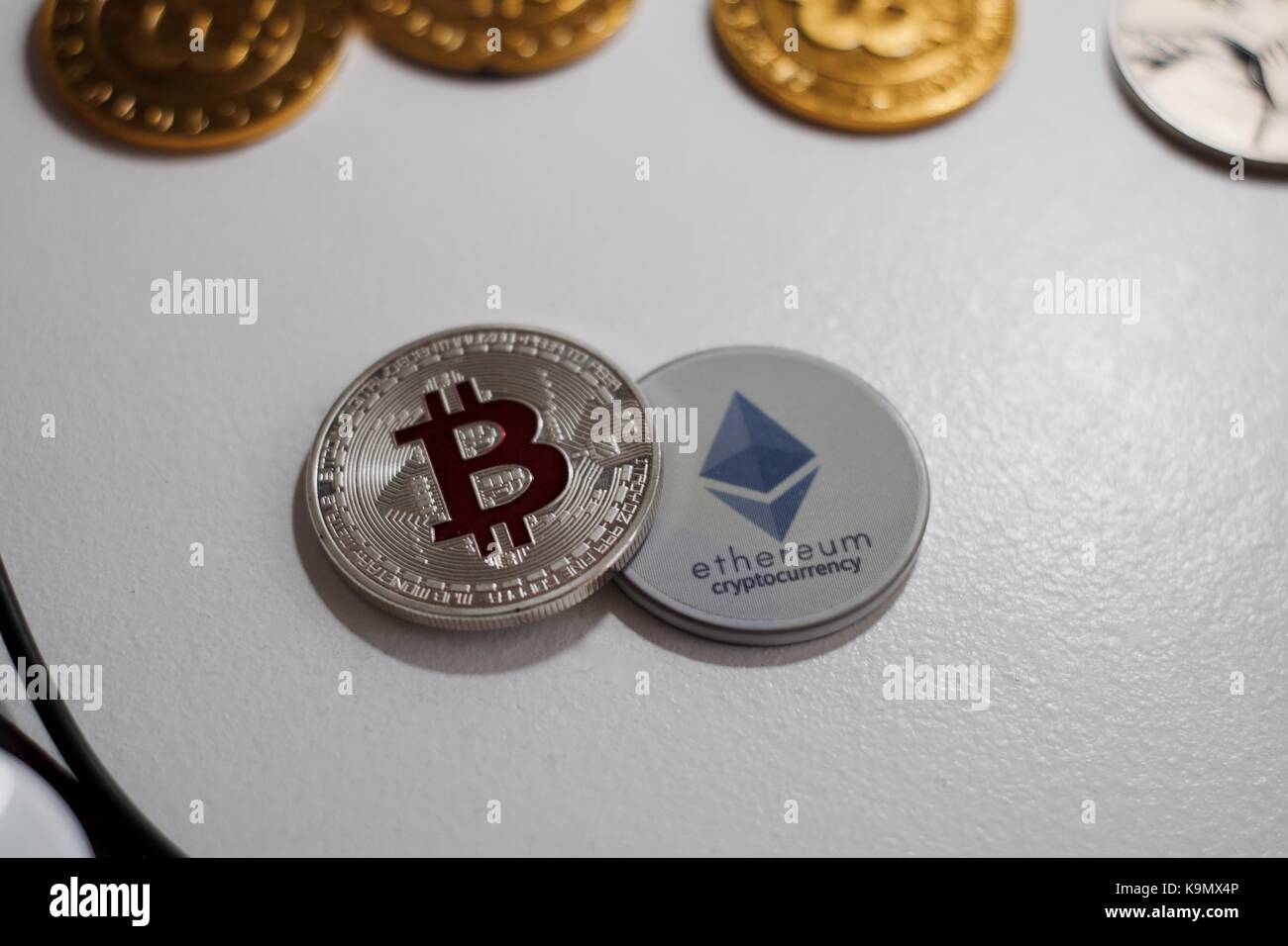 Digital currency physical grey Ethereum coin near gold bitcoins. Stock Photo