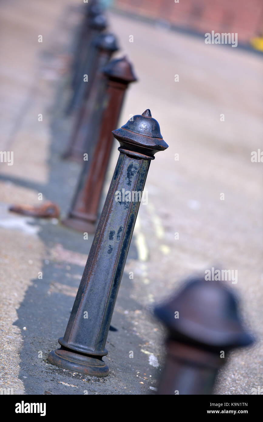 A row of cast iron bollards or stanchions or posts in a line growing gradually out of focus. Stock Photo