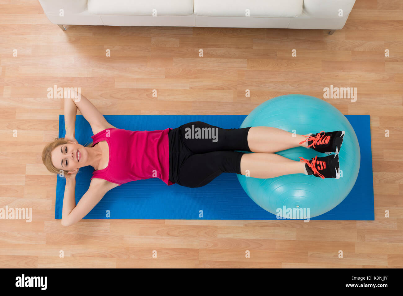 Image of young sport woman sitting at home on yoga mat, doing workout,  stretching fitness exercises on floor in living room, smiling and looking  happy at camera 35338806 Stock Photo at Vecteezy