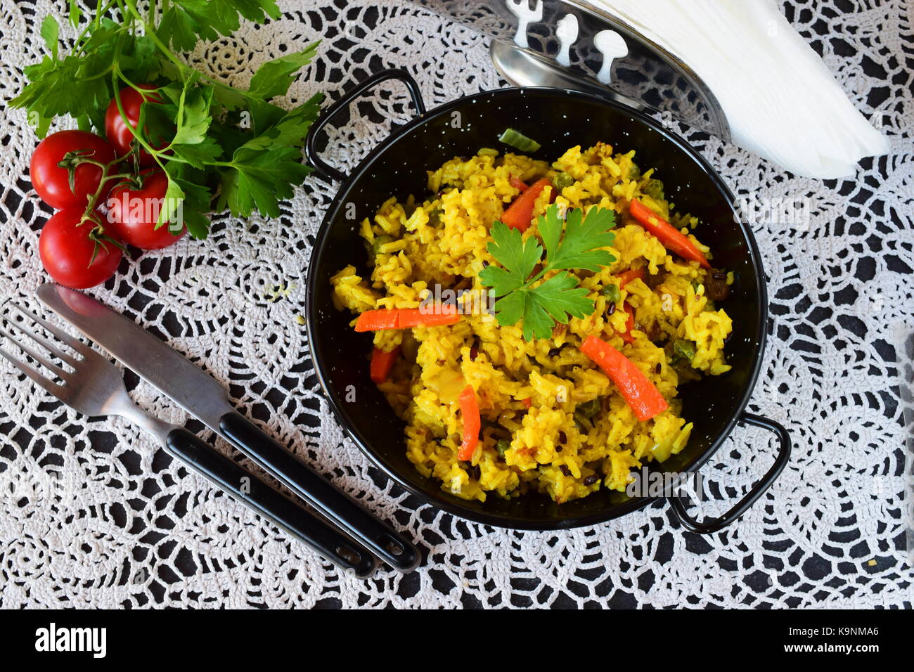 Vegetarian rice with carrots, onions, raisins and olive oil in a black metal bowl. healthy eating concept. Dieting Stock Photo
