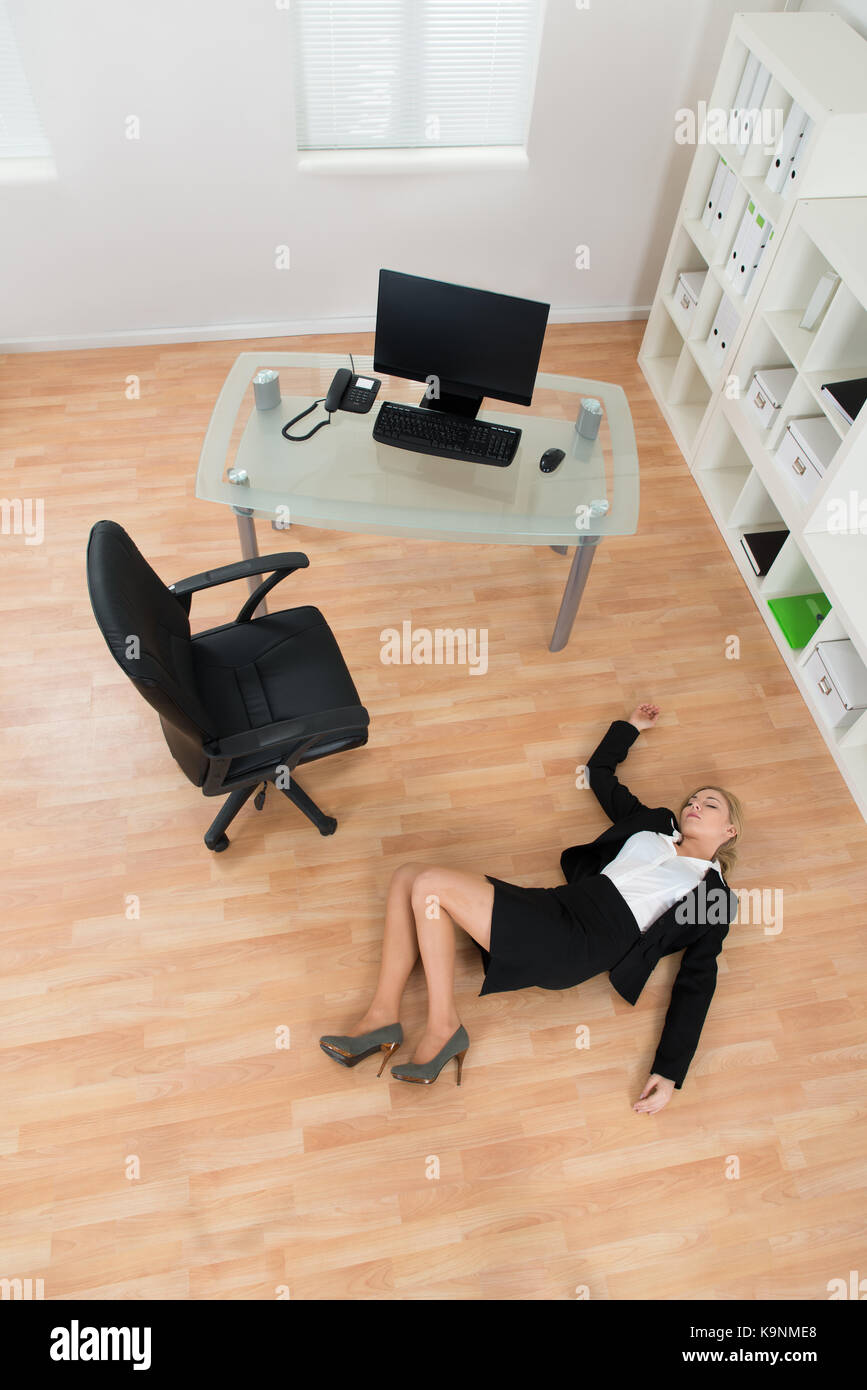 High Angle View Of Young Businesswoman Fainted On Floor In Office Stock Photo