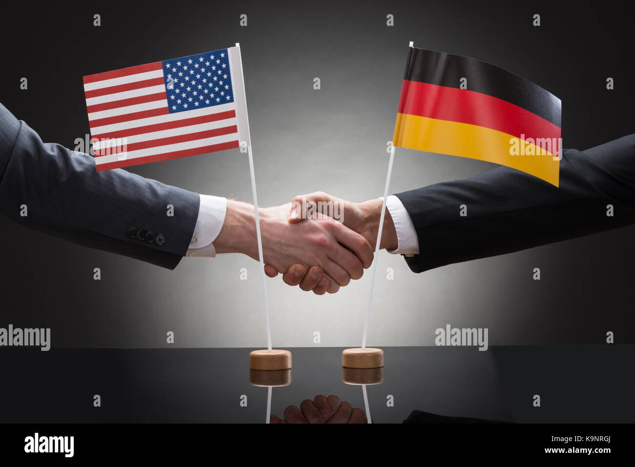 Close-up Of Two Businesspeople Shaking Hands In Front Of Us And Germany Flags Stock Photo