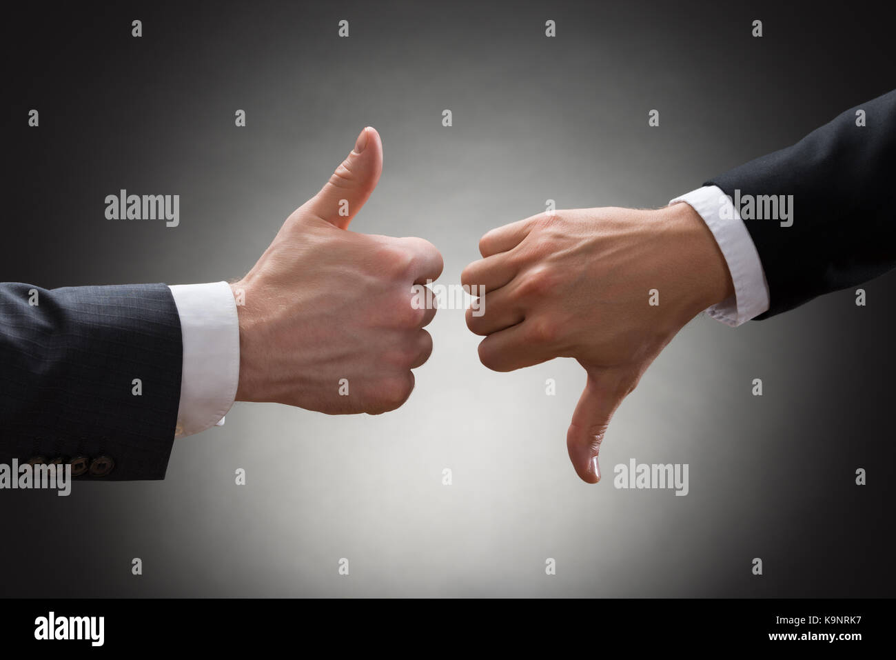 Close-up Of Two Businesspeople Hands Showing Thumb Up And Thumb Down Sign Stock Photo