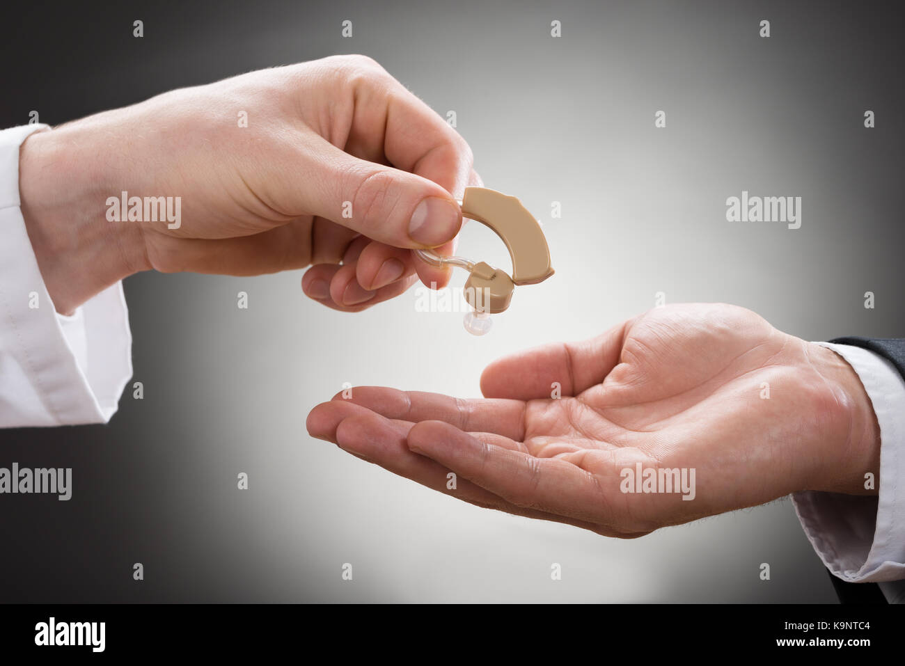 Close-up Of A Doctor's Hand Giving Hearing Aid To Patient Stock Photo