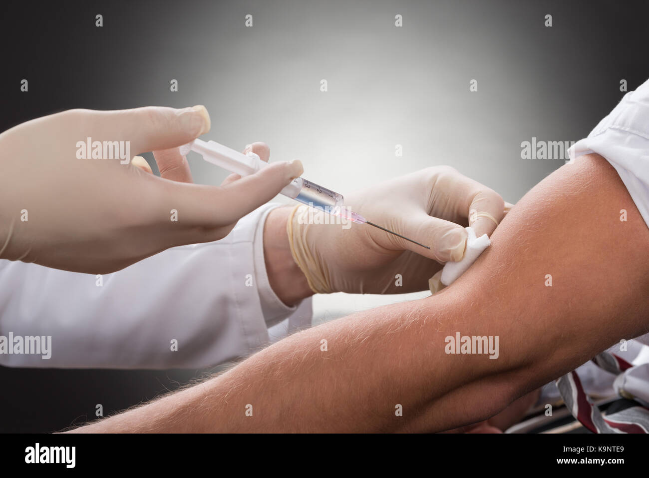 Close-up Of Doctor Injecting Injection On Patient's Arm Stock Photo