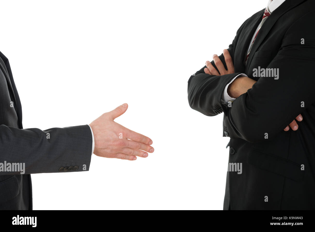 Person Offering Handshake To Businessman With Arm Crossed Over White Background Stock Photo