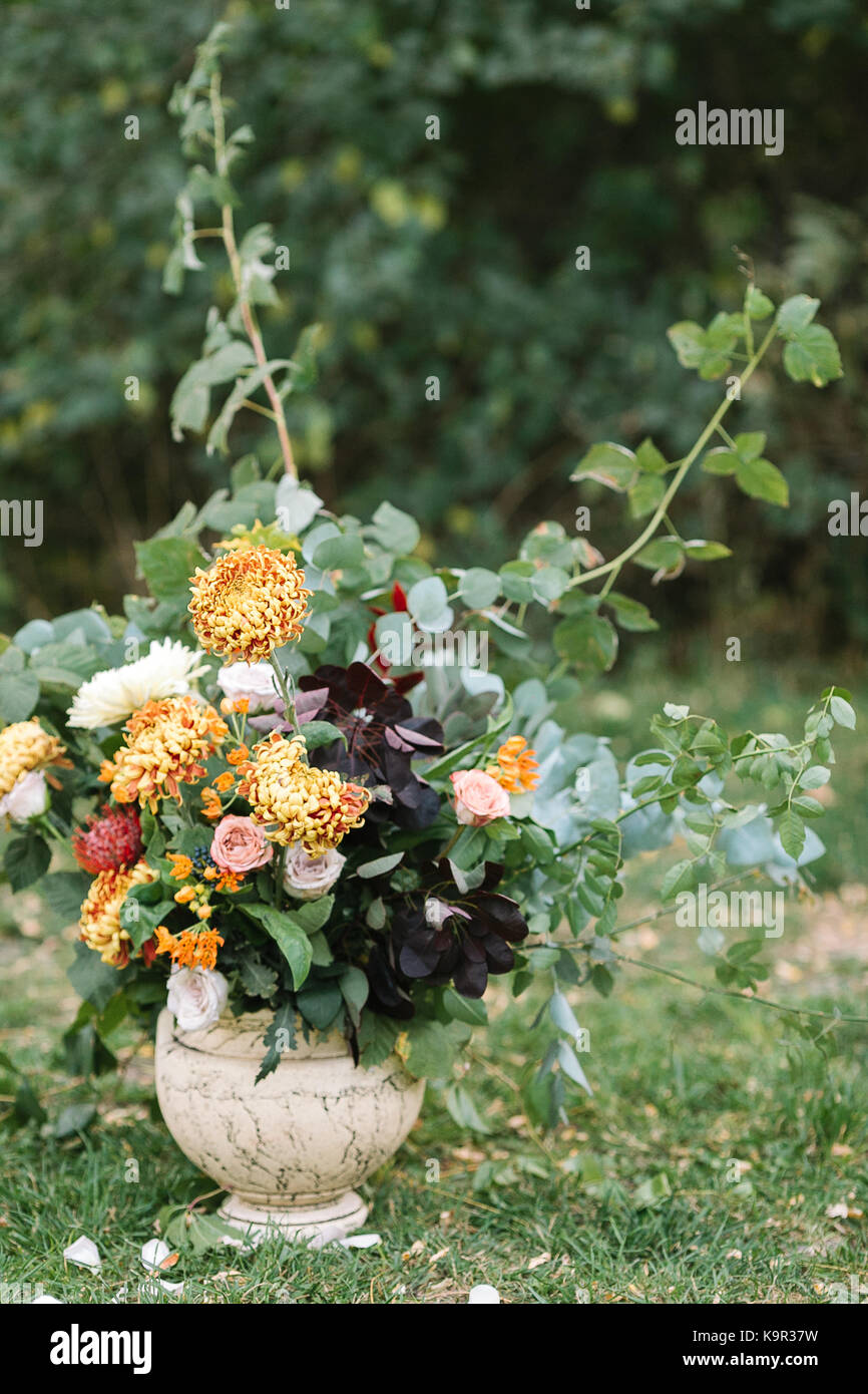 arranging, holidays, surprise concept. on the grass extremely beautiful wedding bouquet of such remarkable flowers as bright orange chrisantemums combined with delicate roses of different colours Stock Photo