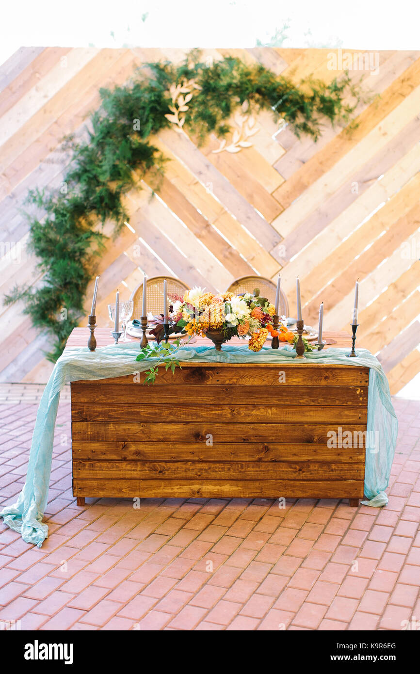 design, celebration, wedding concept. ravishing table for newlyweds decorated with light blue draping, wonderful bouquet of flowers, candles in elegant bronze holders Stock Photo
