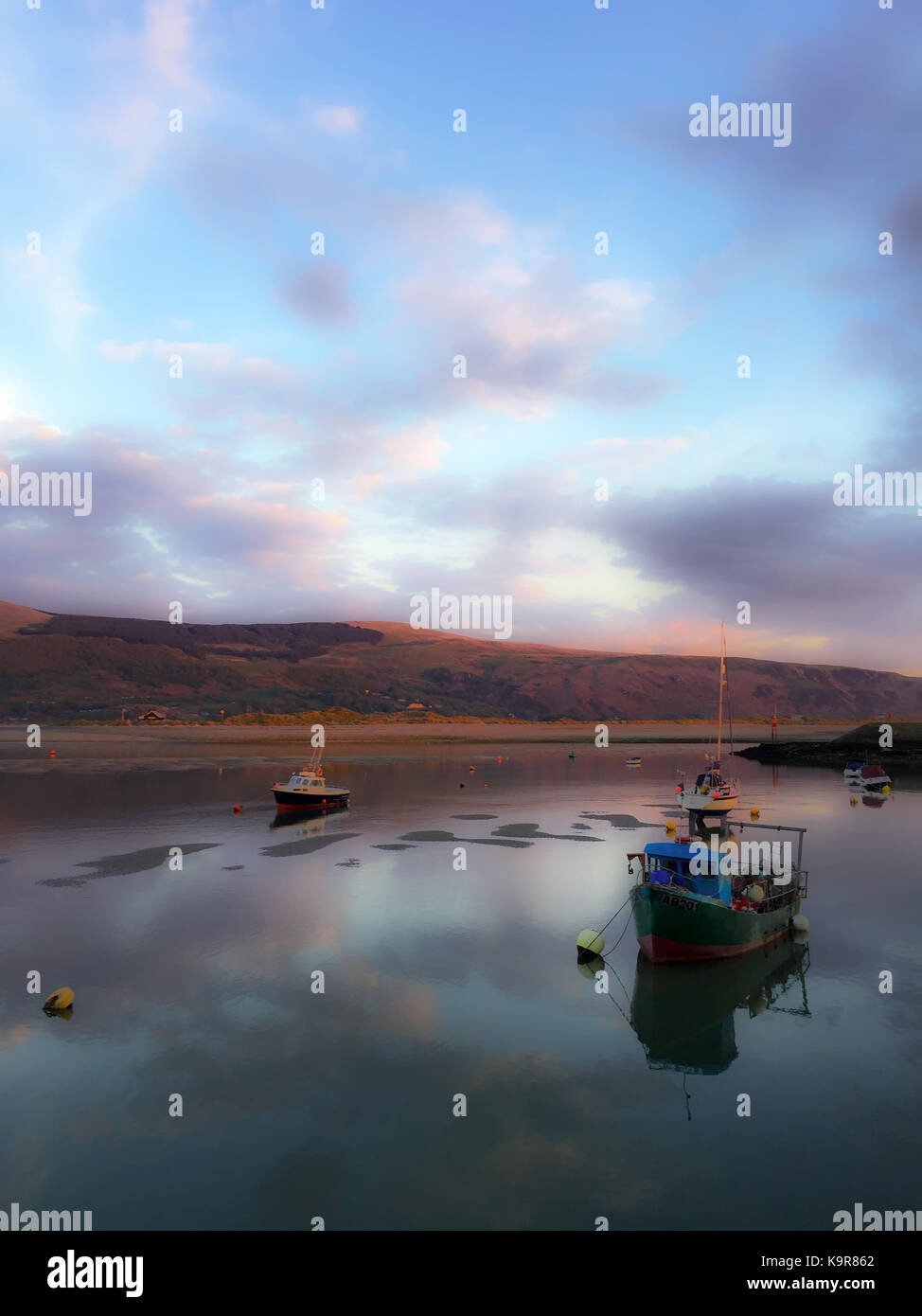 Boats on calm water of Barmouth in Wales as sunset approaches. Stock Photo