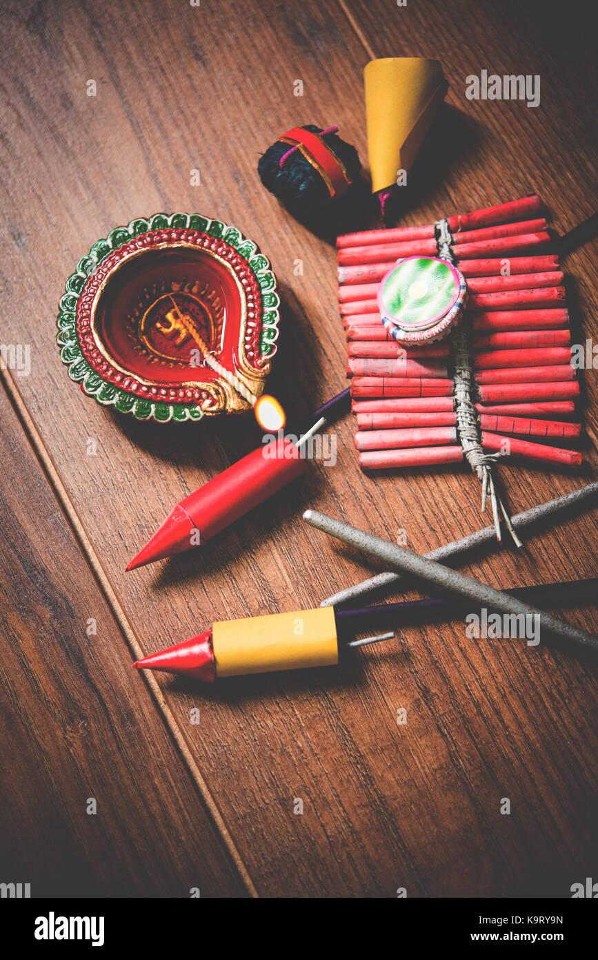 stock photo showing Diwali still life with Diya or oil Lamp and fire crackers like rocket fulzadi, anar and chakri, selective focus Stock Photo