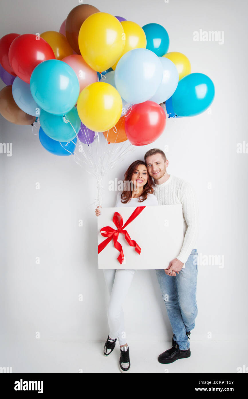 Young smiling couple with balloons and big gift box Stock Photo - Alamy
