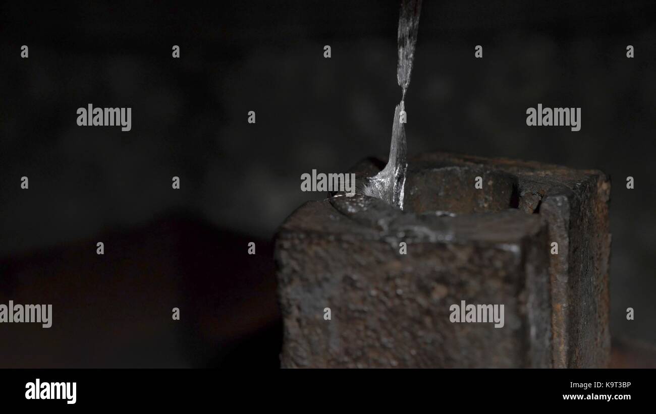 Pouring molten lead alloy into a mold. Manufactory, manual manufacturing of lead alloy