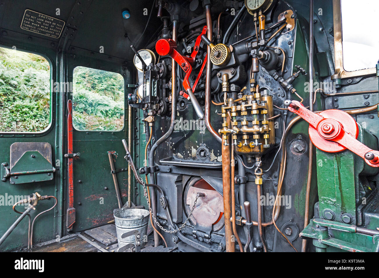 Footplate and cabin of a steam locomotive engine, showing dials, levers, pipes, and opening for coal to feed the boiler. Stock Photo