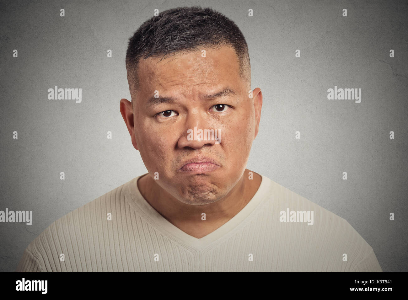 grumpy man isolated on grey wall background Stock Photo