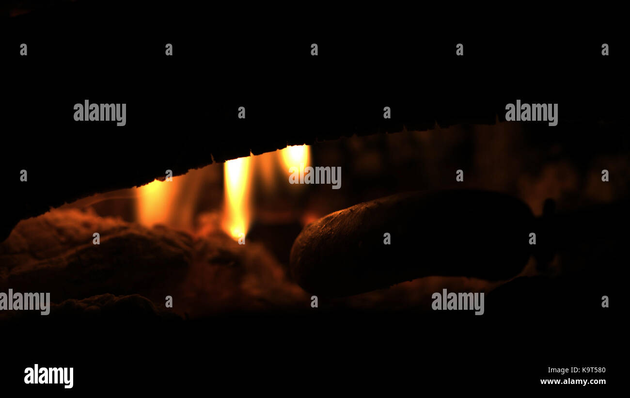 Making and cooking Hot dog sausages over open camp fire. Grilling food