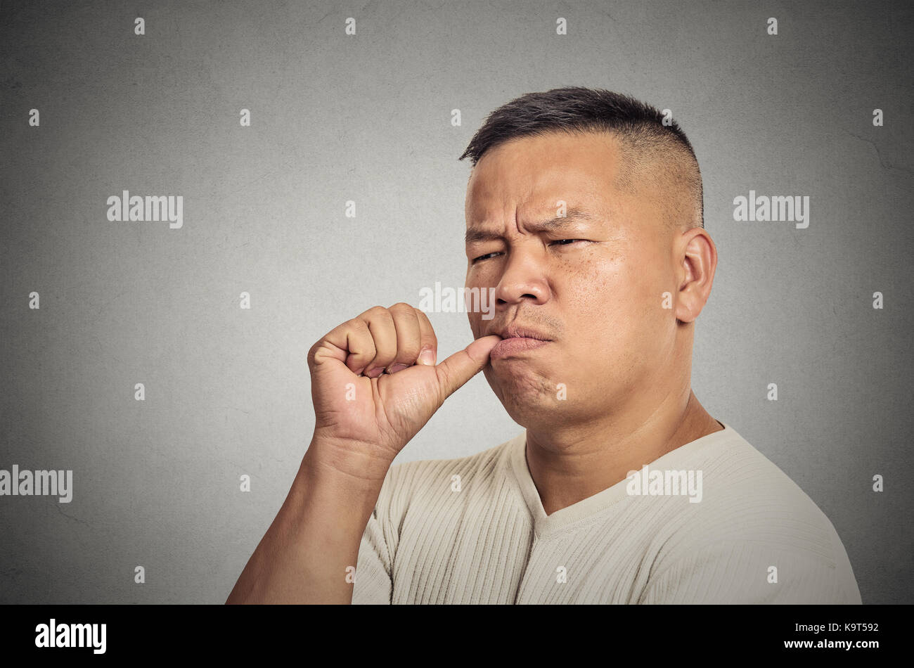 Lazy young man sucking thumb doing nothing isolated on grey wall background. Face expression human emotion Stock Photo