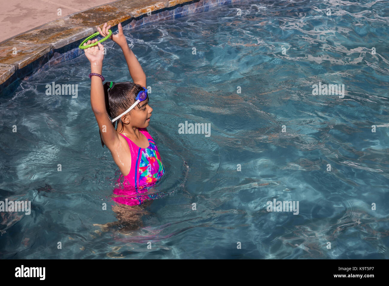 1, one Hispanic girl, playing in swimming pool, swimming pool, freshwater swimming pool, Castro Valley, Alameda County, California, United States Stock Photo