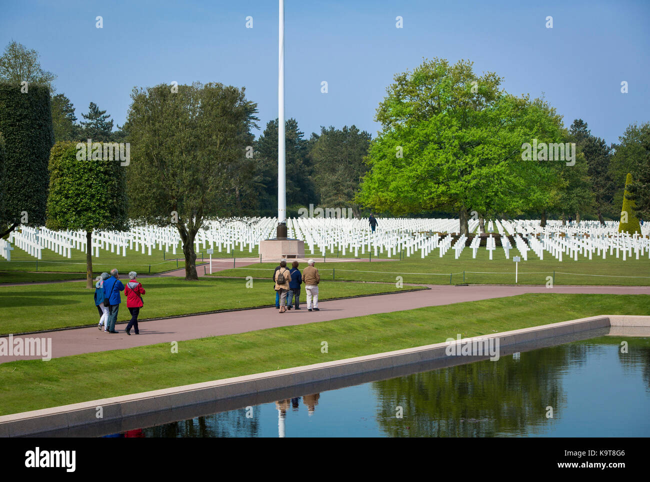 Visitors walk through the perfectly manicured garden and lines of crosses at the American Cemetery, Colleville-sur-Mer, Normandy France Stock Photo