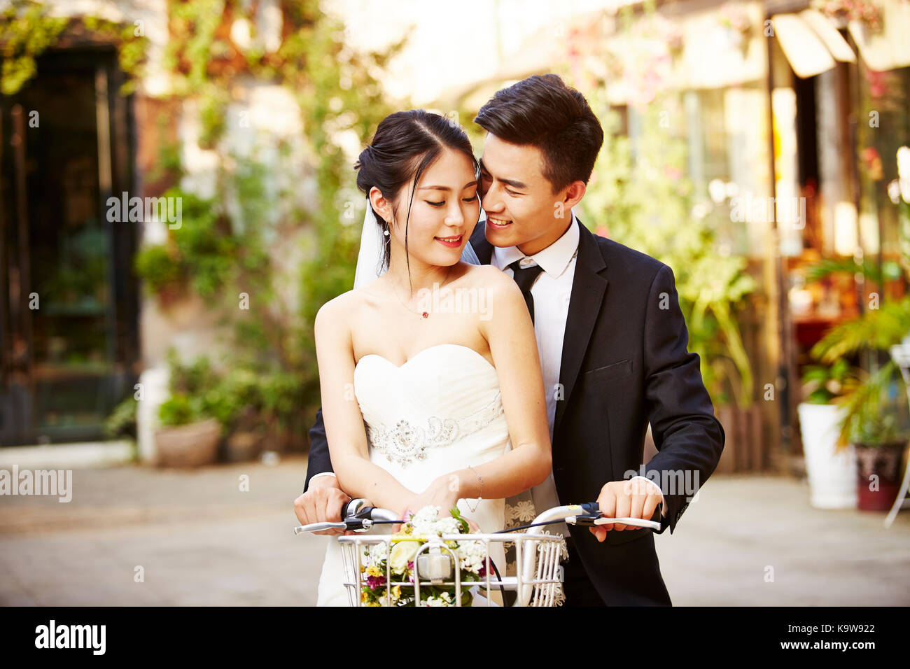 happy newly wed asian couple having fun riding a bicycle. Stock Photo