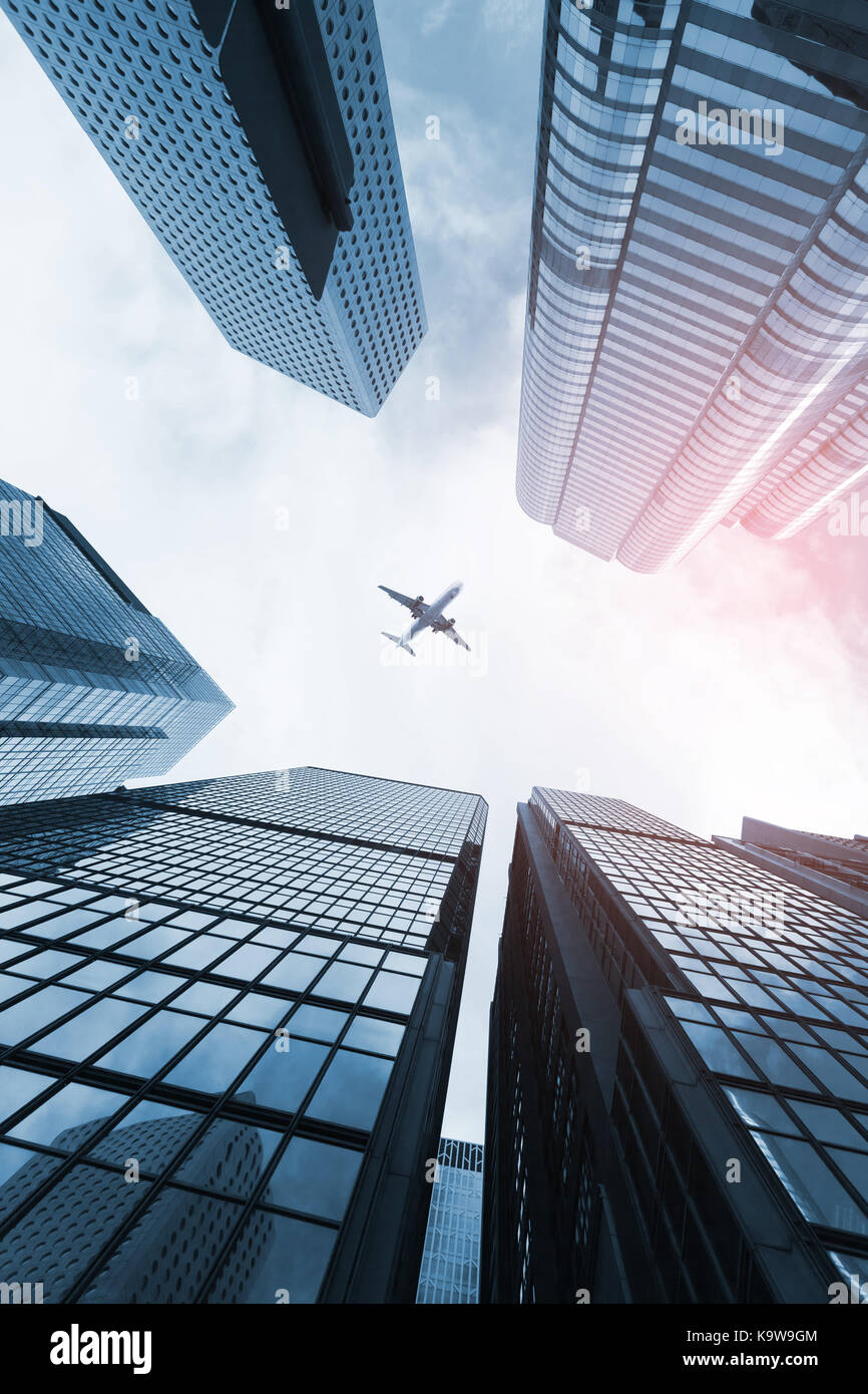 Modern skyline with passenger plane flying over business skyscrapers, high-rise office buildings of Hong Kong city Stock Photo